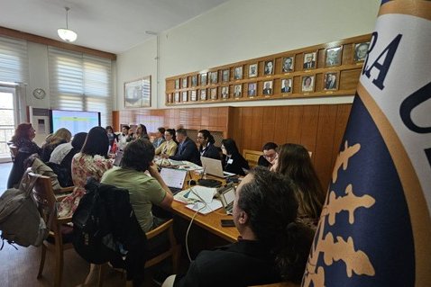 Participants are seated at a long table with their computers.