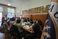 Participants are seated at a long table with their computers.