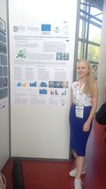 A woman is standing next to a poster and presenting the results.