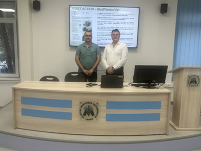 Two men on a podium stand in front of a screen.